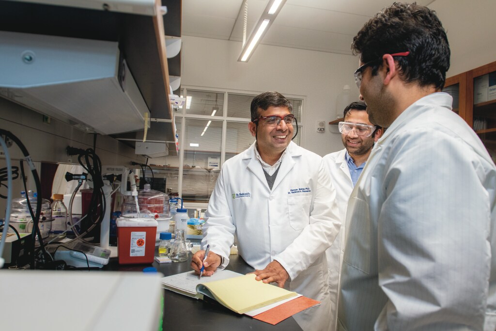 Raman Bahal, Associate Professor of Pharmaceutics talking with his graduate students (Sean Flynn/UConn Photo)