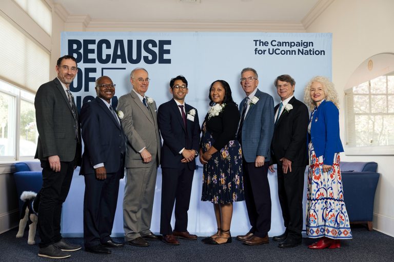A group of CLAS alumni stand with UConn President Radenka Maric in front of a backdrop that reads 