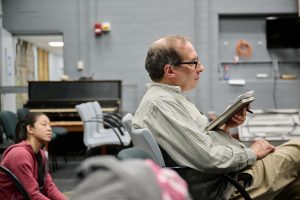 A man sits in a chair holding a notebook