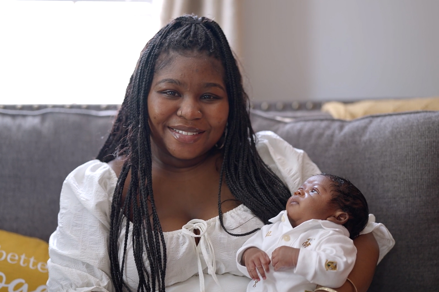 A woman in white sitting holding her newborn son