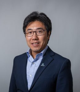 A professional portrait of a man wearing a blue suit.