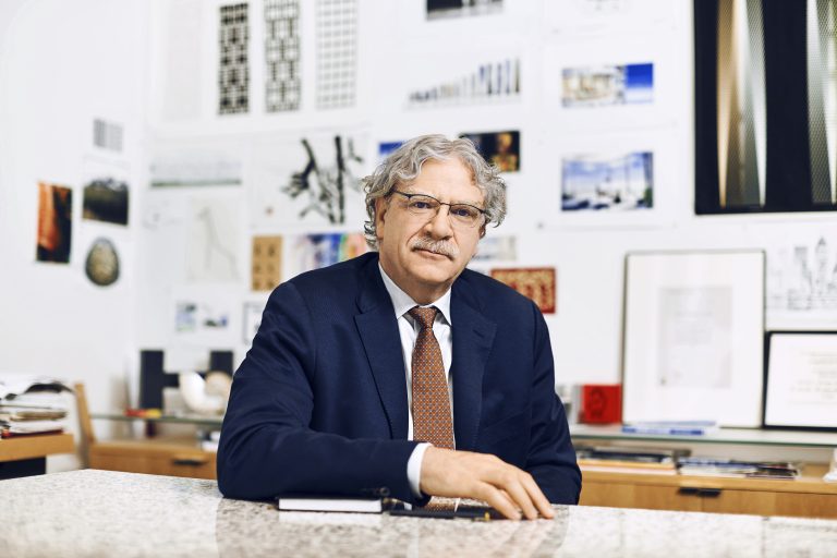 A man in an office with architectural design and engineering posters behind him.