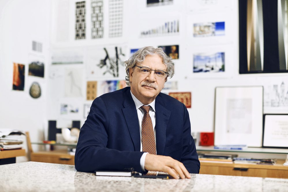 A man in an office with architectural design and engineering posters behind him.
