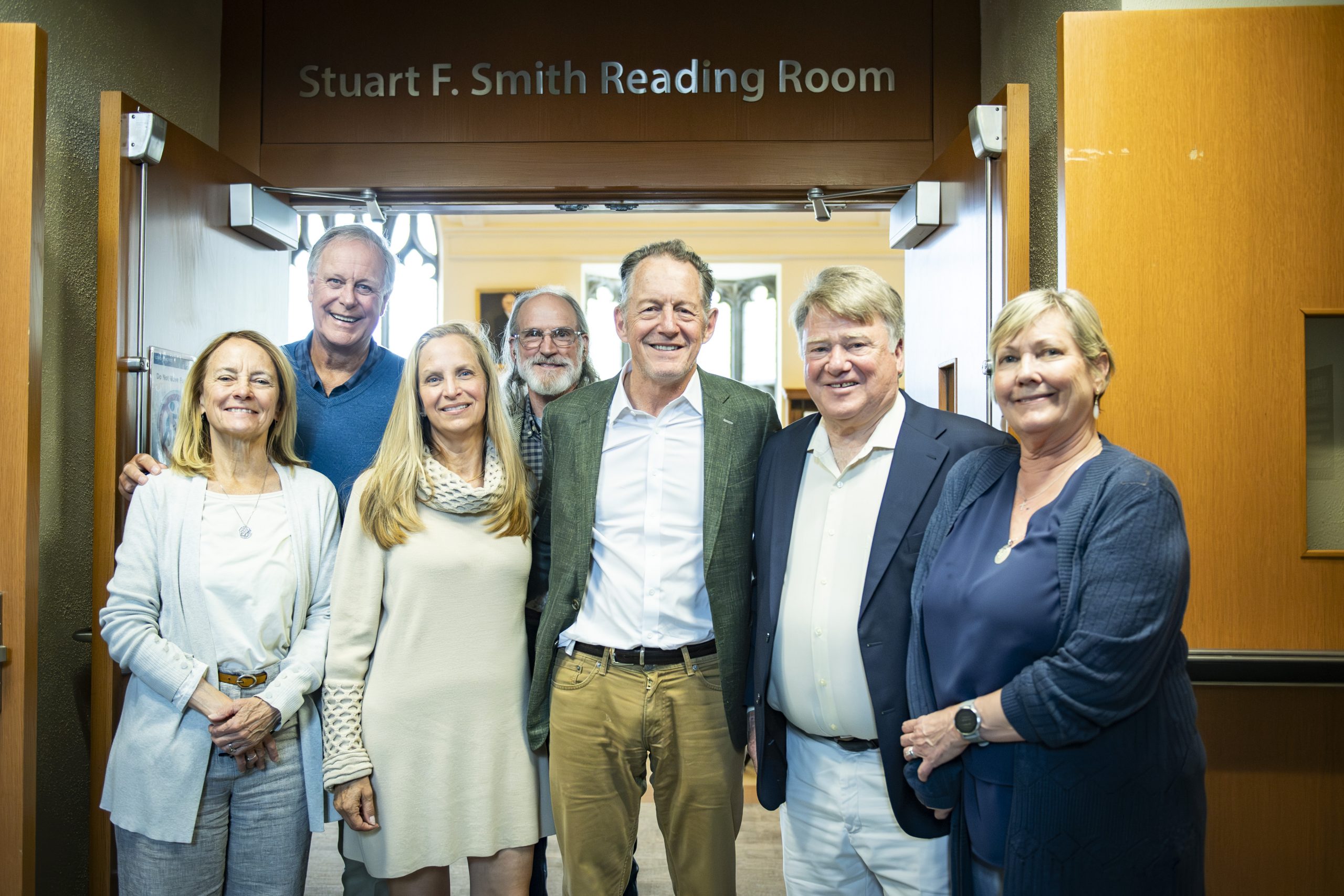 A group of seven people stand in front of the entrance to a room.