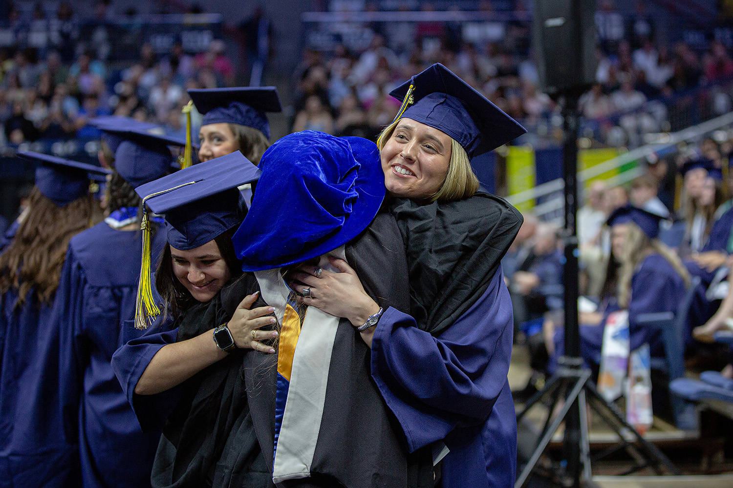 Graduates hug an advisor during CLAS commencement ceremony.