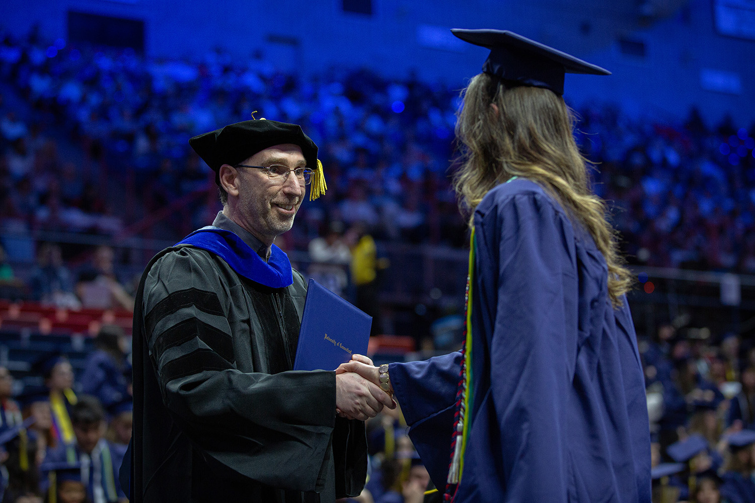 Dean Ofer Harel shakes hands with a graduate at Gampel Pavilion.