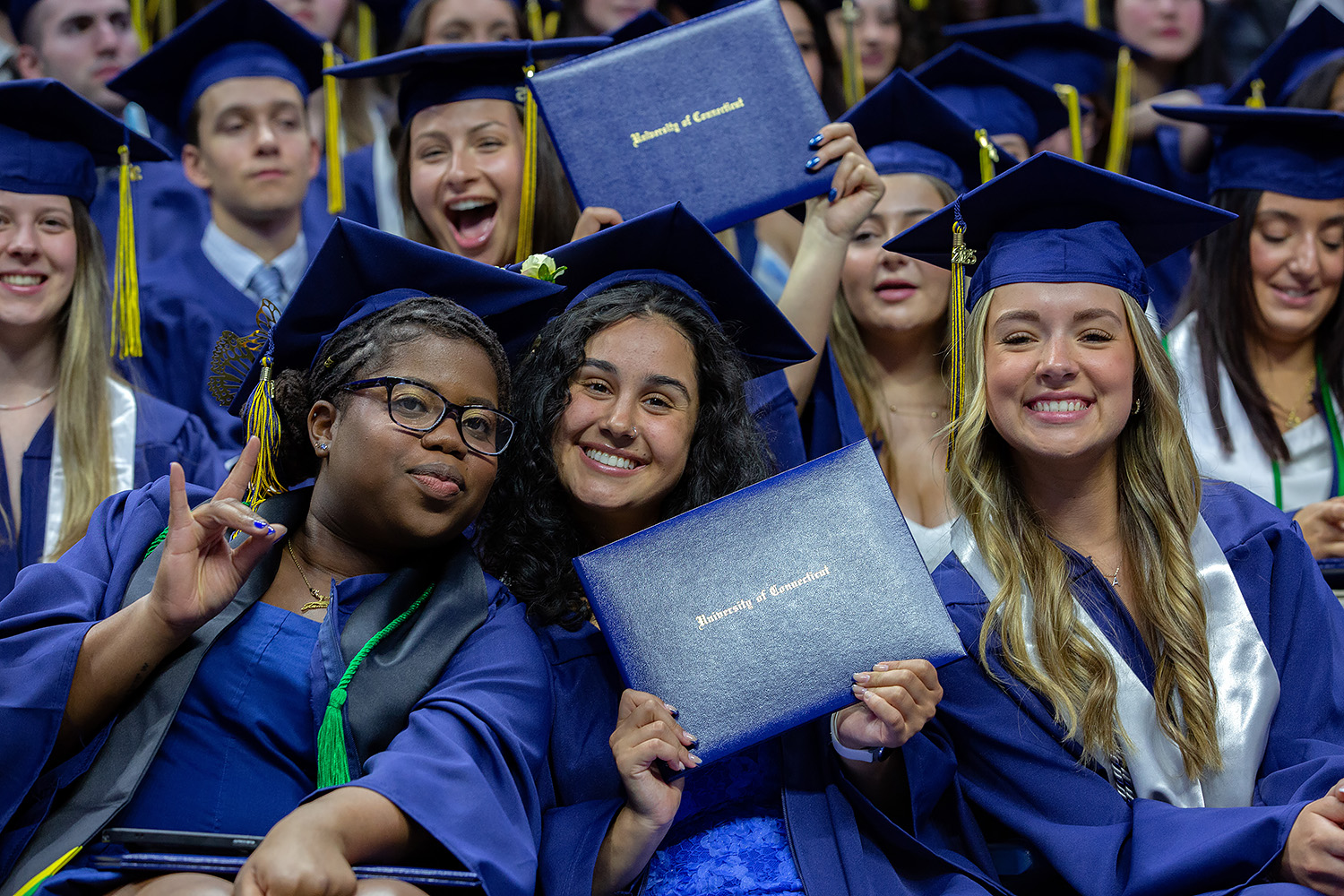 Graduates holding up their diplomas.