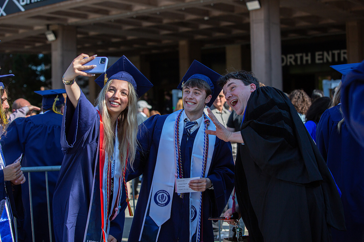 Graduates pose for a selfie while in line outside Gampel Pavilion.