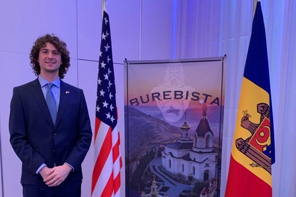 A boy standing next to a U.S. and Germany flag
