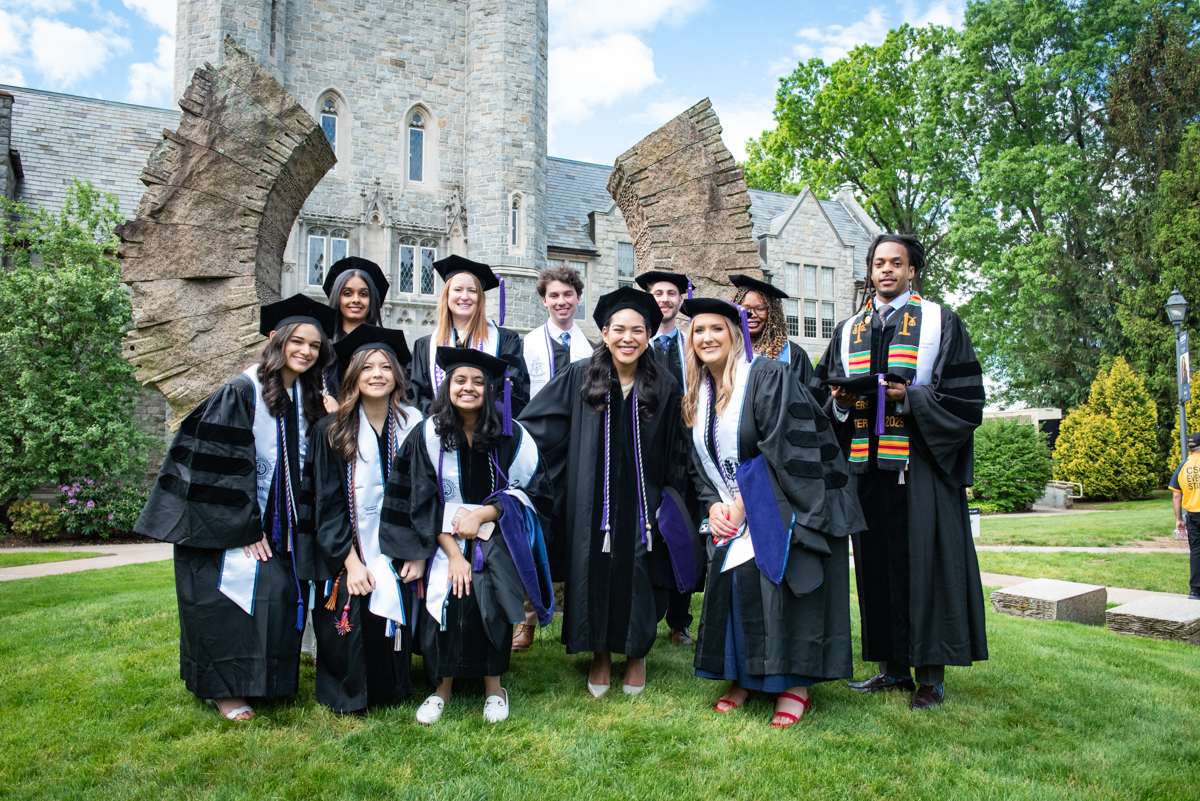 A group of graduates poses in front of the Middle Path sculpture