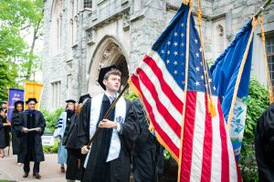 A graduate carries the American flag in the procession
