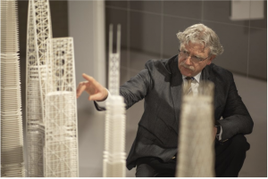 A man pointing at small-scale models of tall buildings.