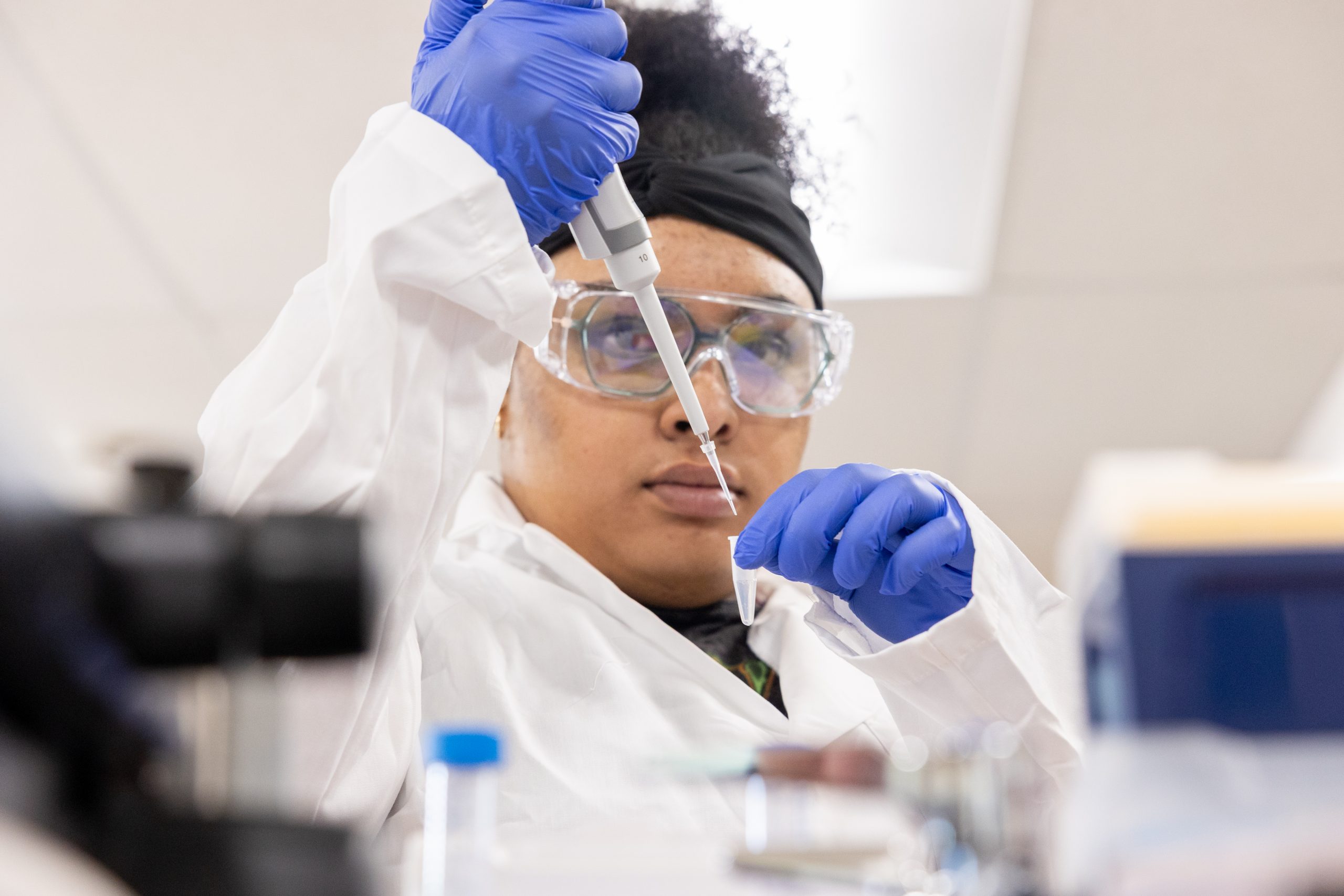 A close-up shot of a student carefully concentrating on using a pipette to move water into a small vial