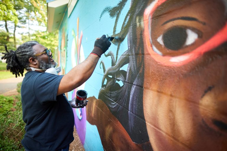 Andre Rochester painting a mural outdoors