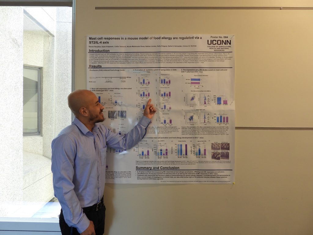 A man points at a chart on an academic poster