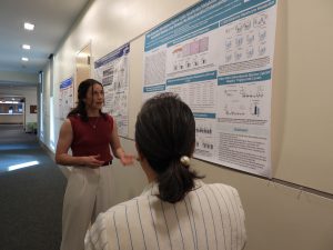 Two women discuss an academic poster on the wall