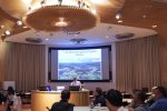 A man giving a presentation in a circular room full of people