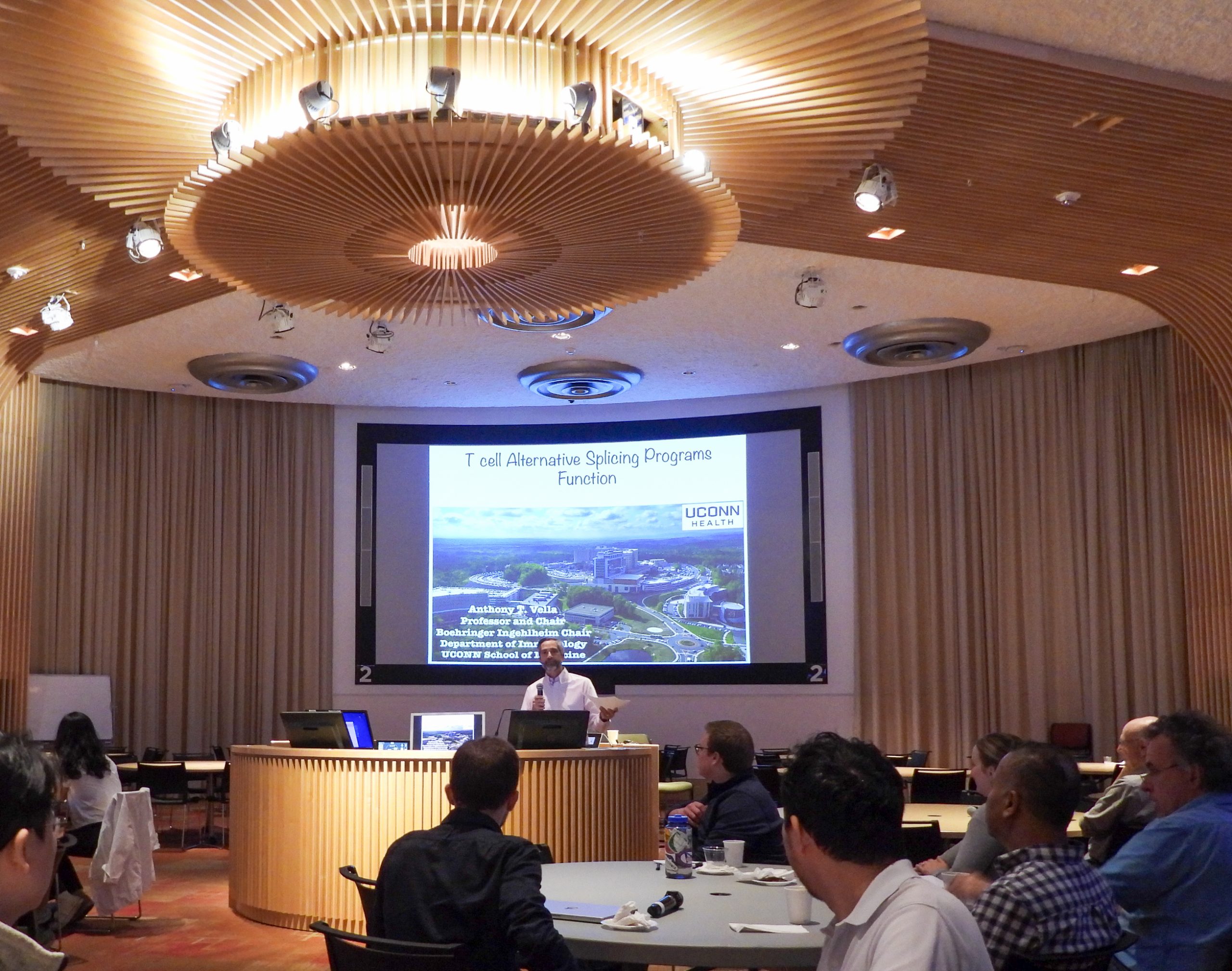 A man giving a presentation in a circular room full of people