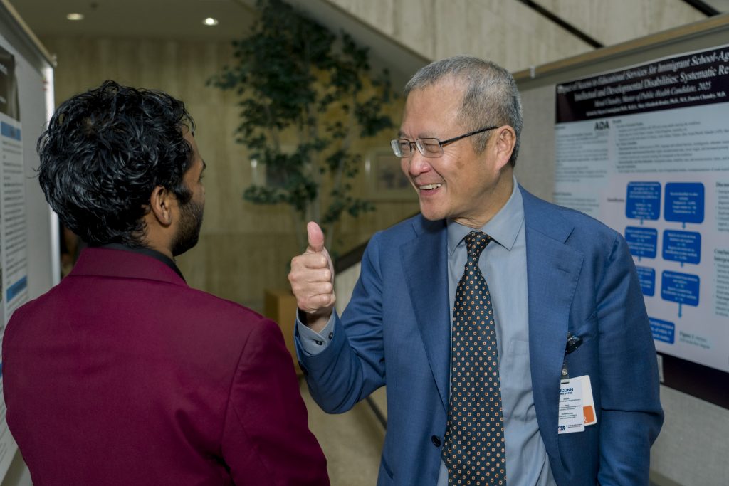 Dr. Liang applauding the research poster of a public health student trainee at UConn School of Medicine. (Photo by Tharun Palla/Public Health Sciences)