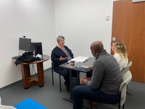 Three people sit at a table talking.