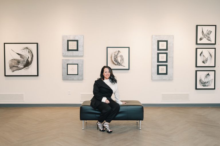 A woman is seated in an art gallery.