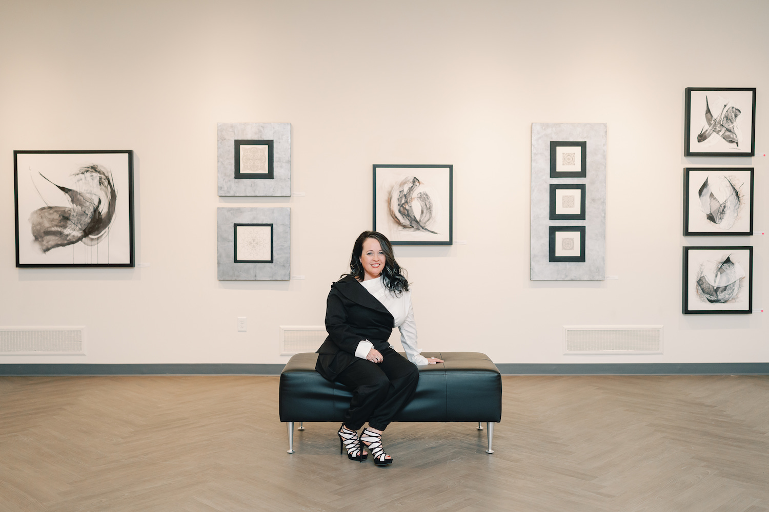 A woman is seated in an art gallery.