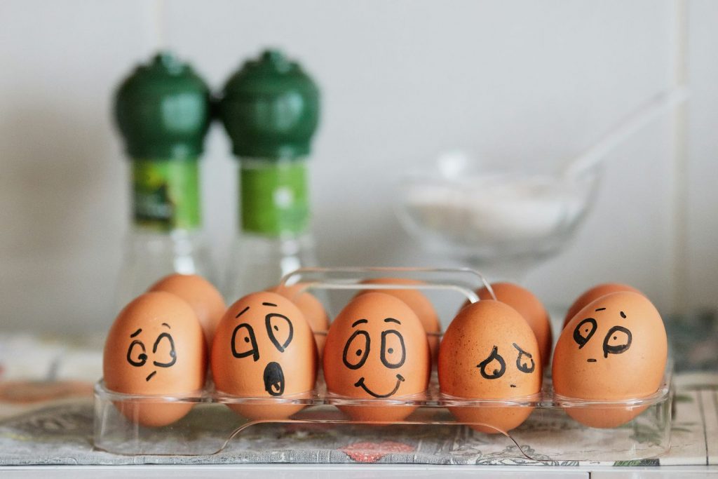 Eggs in a carton with faces drawn on showing different emotions