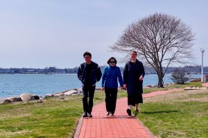 Three people walking outside next to the water