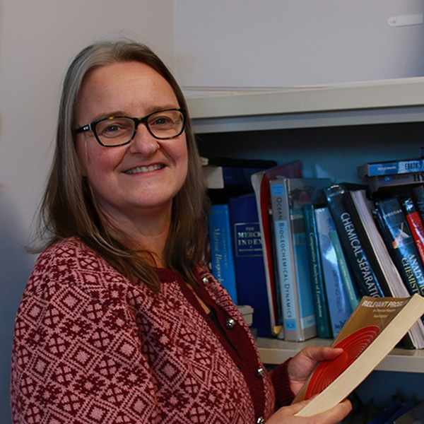 JULIE-GRANGER-FULBRIGHT_uctedit A woman with glasses holding a book by a bookshelf