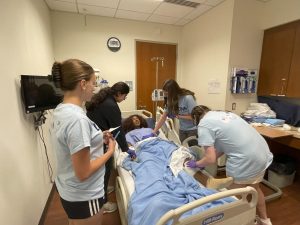 High school students in the Early Introduction to the Nursing Profession (EINP) program with the simulation mannequin on June 26, 2025. (Aime Liggett/UConn Photo)