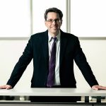 robert-bird-fulbright_UCTedit A man standing in a suit leaning on a table