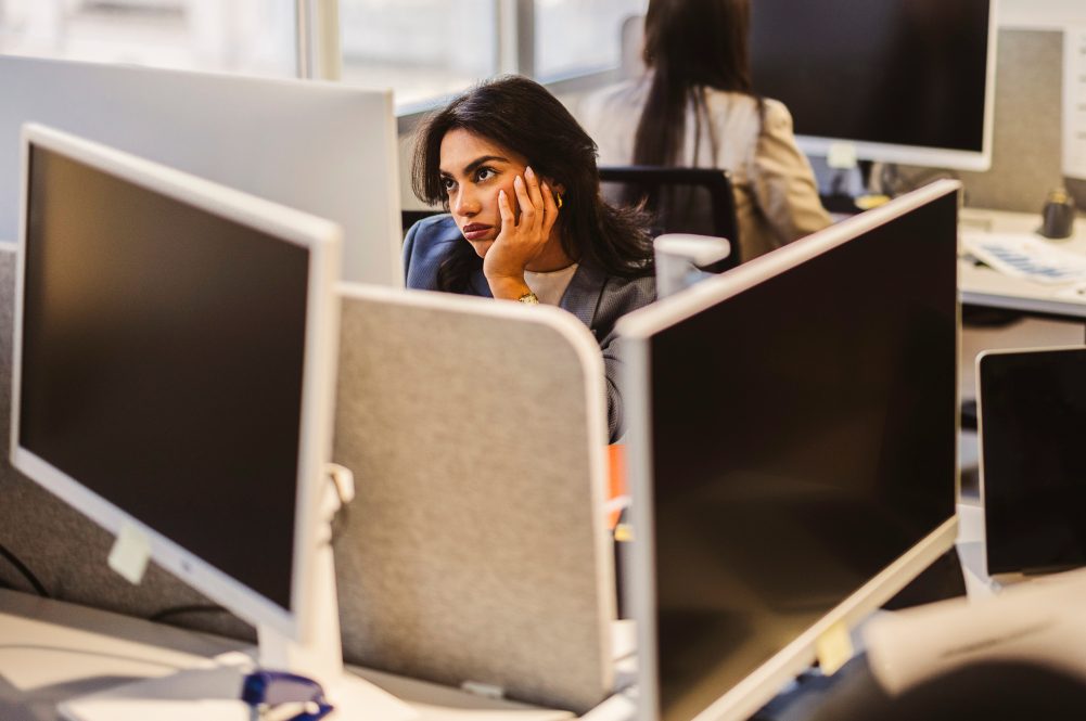 Bored businesswoman resting her chin on her hand while gazing away.