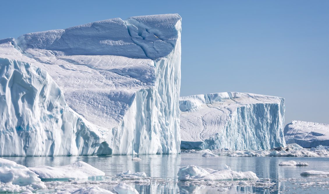 Towering great icebergs in an ocean on a clear sunny day