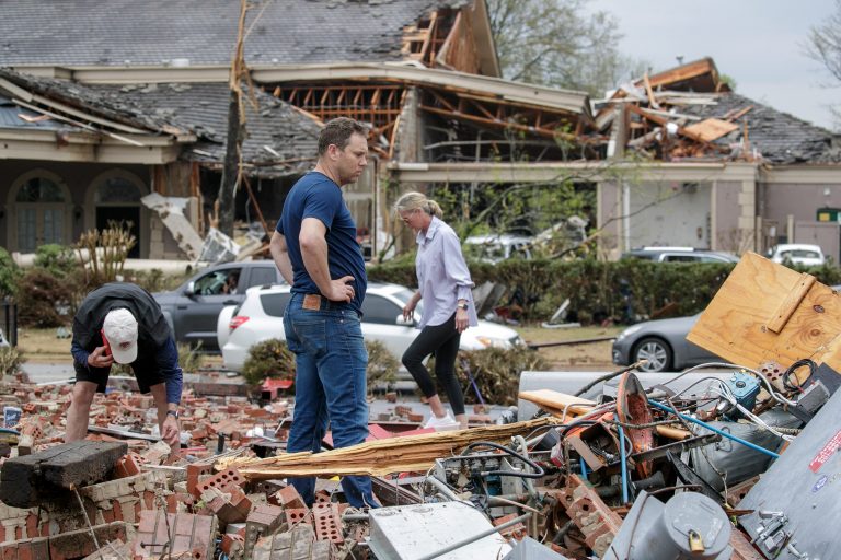 People search through the rubble of a destroyed business following a tornado strike.