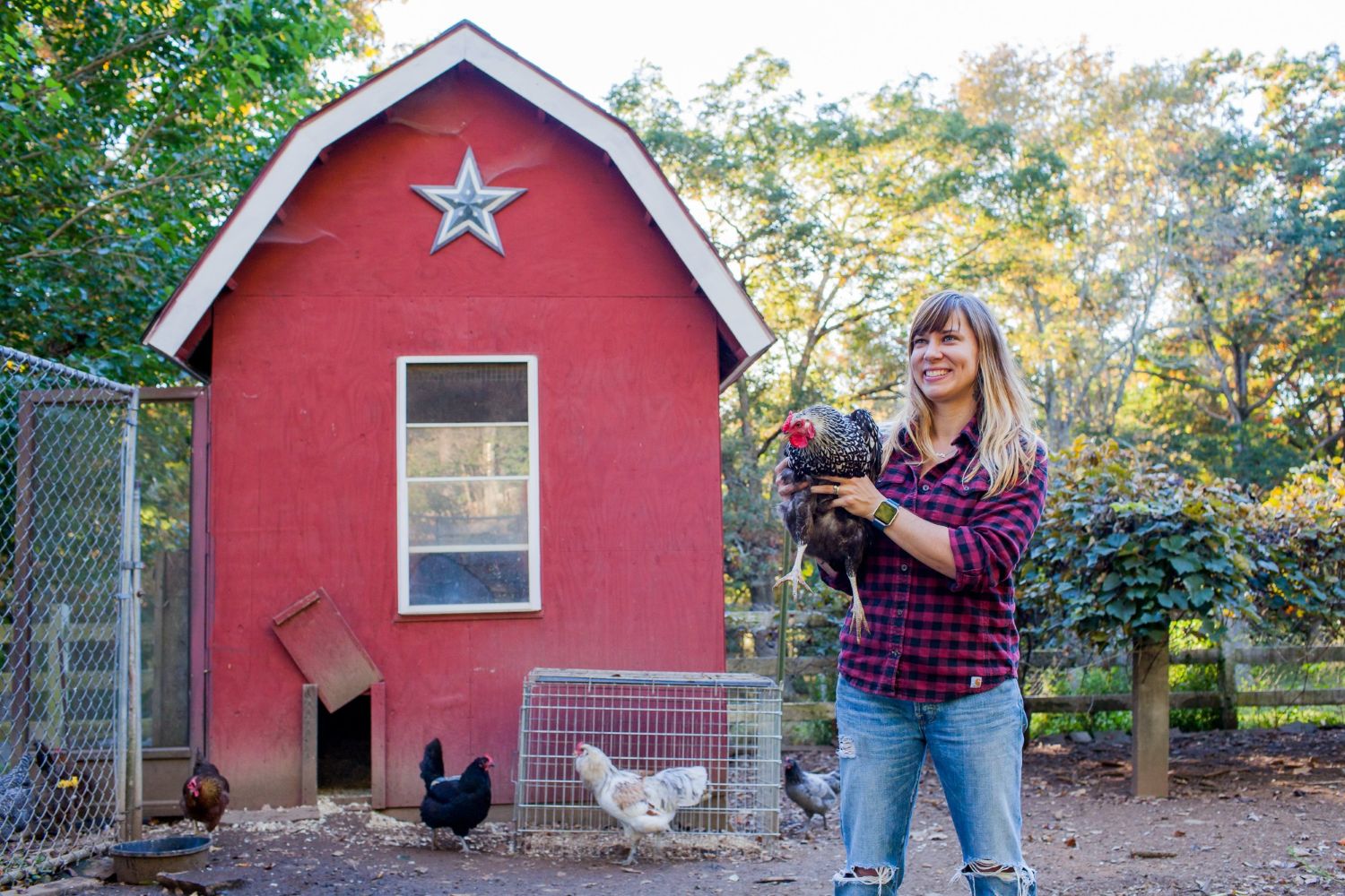 Woman smiles on a farm holding a chicken