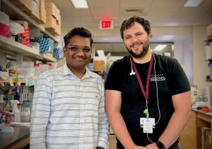 Two males standing in a lab posing for a photo