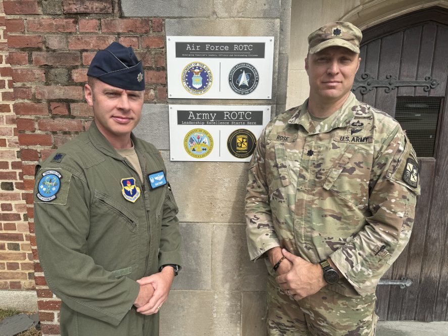 Two ROTC leaders in front of a brick building.
