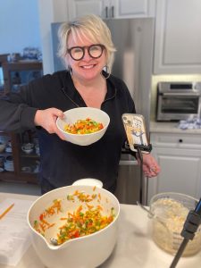 A woman holds up a bowl of salad.