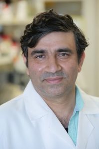 A close-up photo of a man in a labcoat
