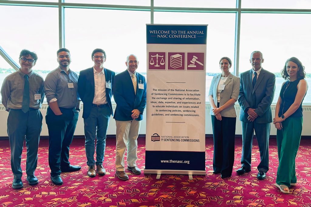 Members of the IMRP and the Connecticut Sentencing Commission stand in front of a conference banner.