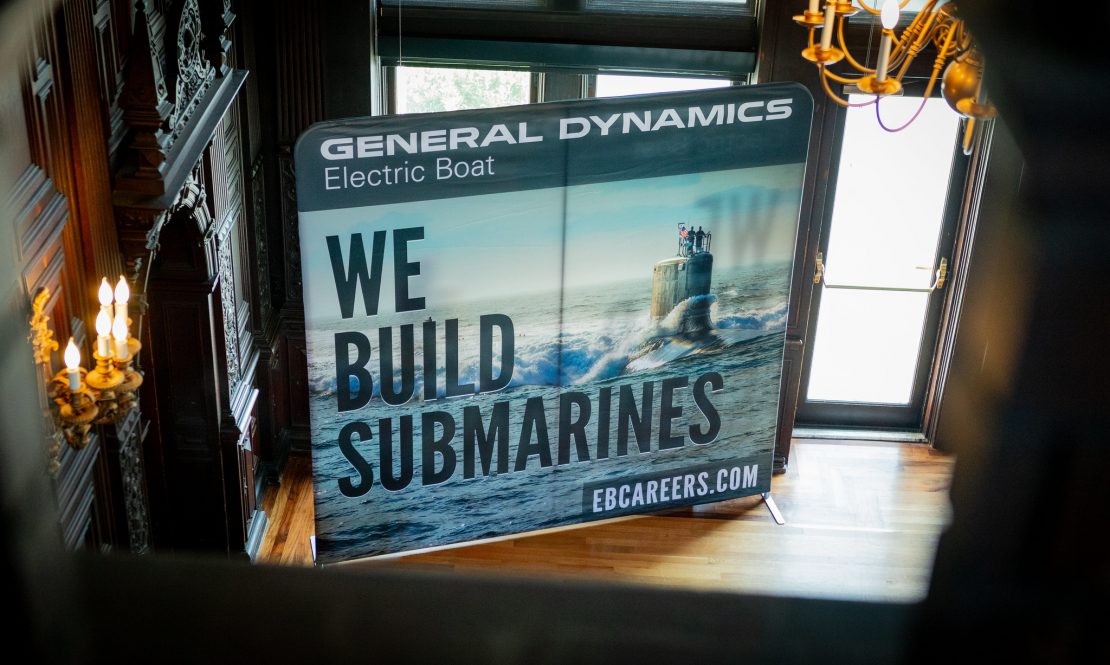 A banner for General Dynamics Electric Boat reads "We Build Submarines" with a photo of a submarine at sea.