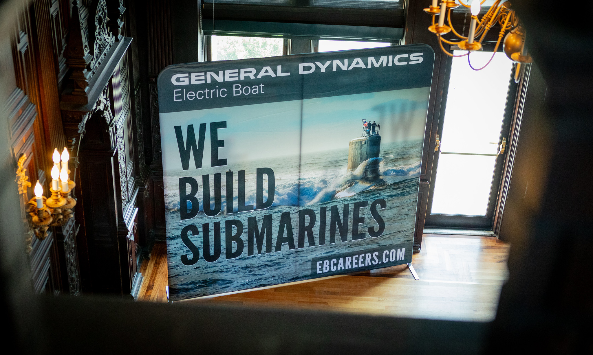 A banner for General Dynamics Electric Boat reads "We Build Submarines" with a photo of a submarine at sea.
