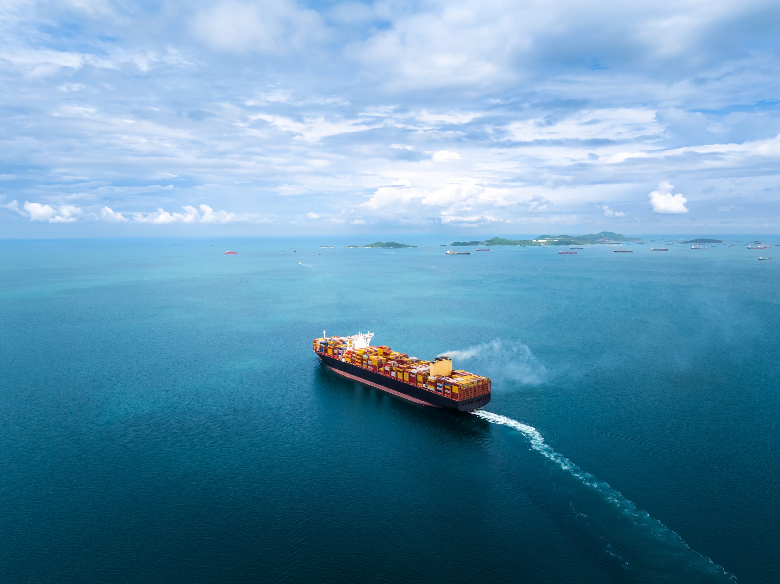 A container ship sailing outward toward an open sea.