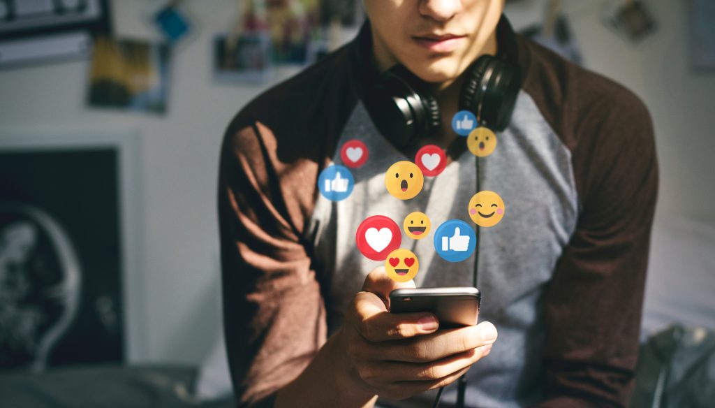 Young man looking at his phone wearing headphones around his neck