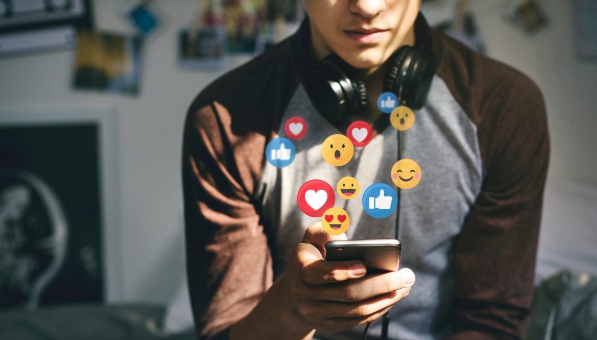 Young man looking at his phone wearing headphones around his neck