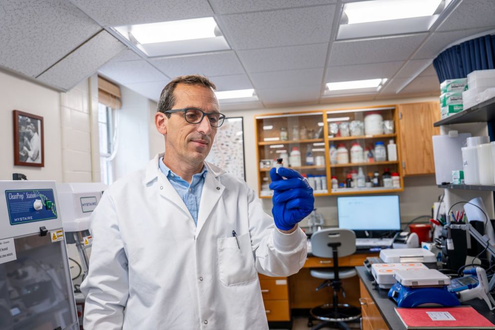 Scientist in a lab holding a small vial