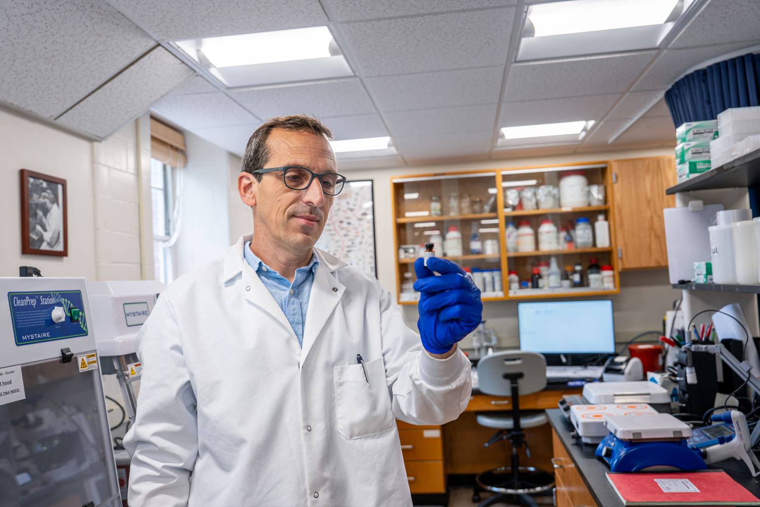 Scientist in a lab holding a small vial