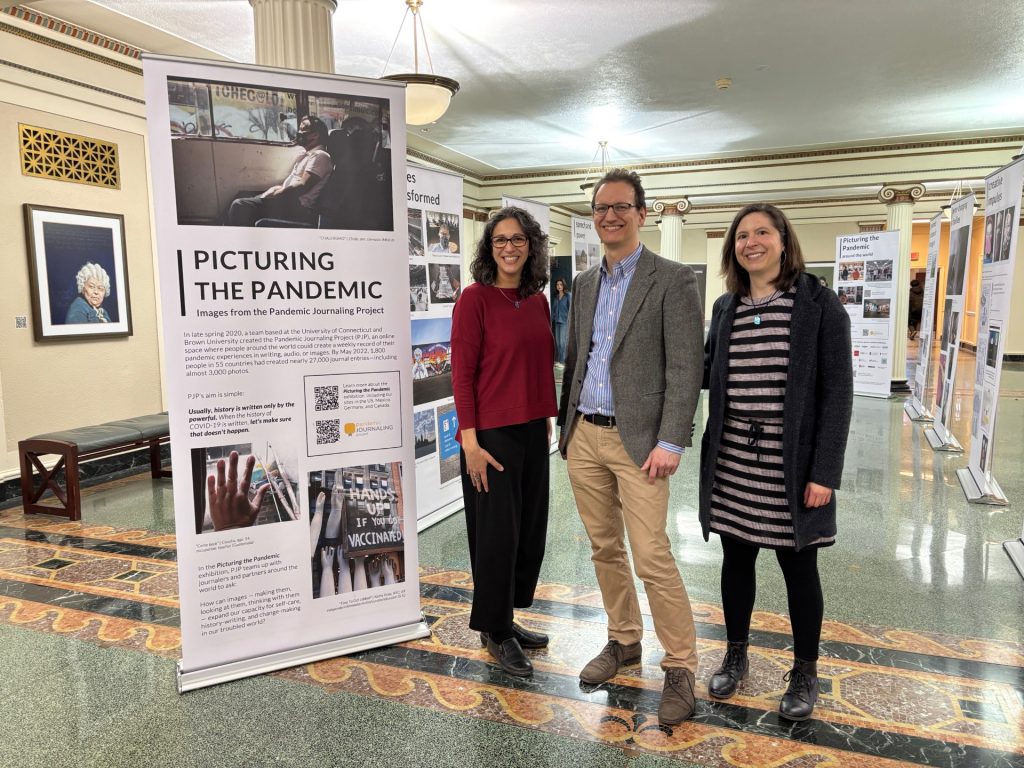 Three people standing next to a large display devoted to the Pandemic Journaling Project.