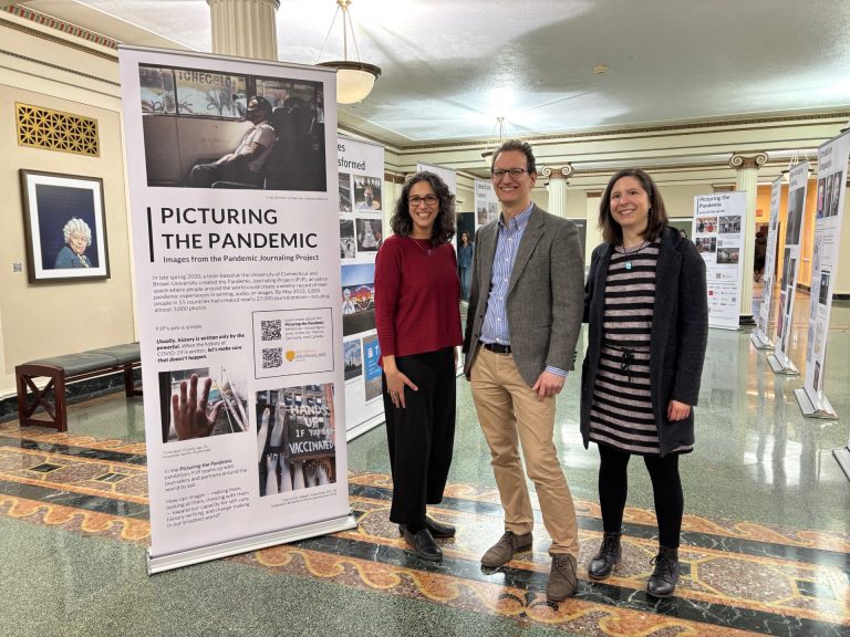 Three people standing next to a large display devoted to the Pandemic Journaling Project.