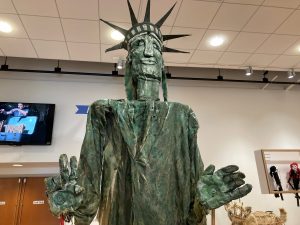 A green-painted burlap, newspaper, tape, and cardboard abstract puppet of the Statue of Liberty.